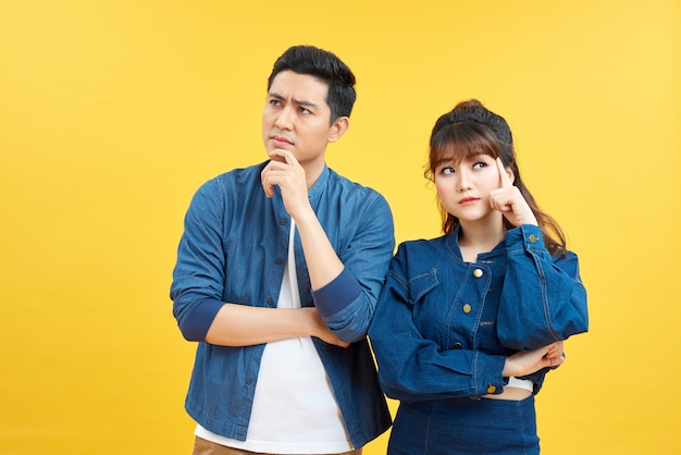 serious man and woman in casual wear touching chins and looking aside isolated over colorful background