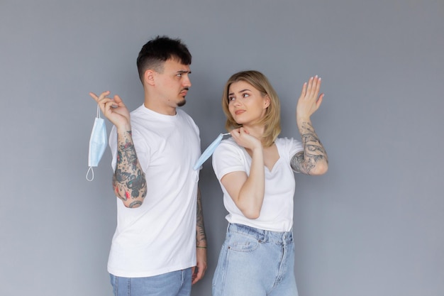 Serious man and woman with crossed hands standing back to back after quarrel wear medical mask