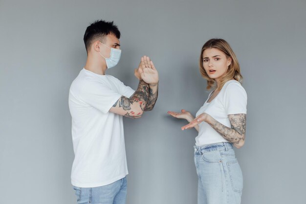 Serious man and woman with crossed hands standing back to back after quarrel wear medical mask