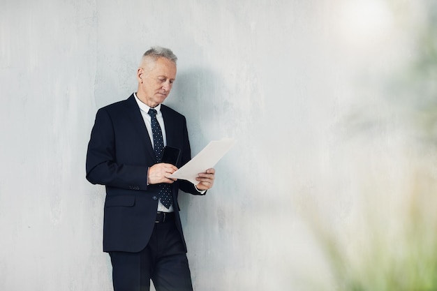 Serious mature businessman examining document