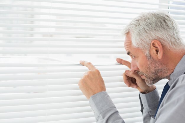 Serious mature businessman peeking in the office