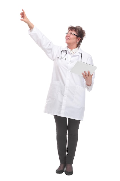 Serious mature doctor in lab coat holding tablet and pointing on white background