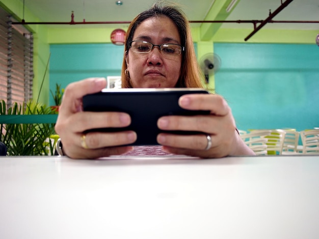 Photo serious mature woman using phone on restaurant table