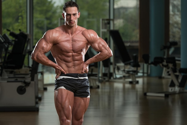 Serious Men Standing In The Gym And Flexing Muscles