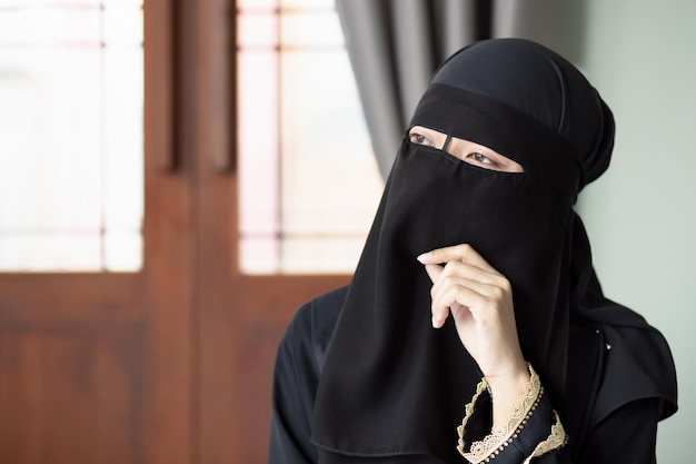 難しい考えや計画を持って考えているniqabベールを覆っている顔を持つ深刻な中東のイスラム教徒の女性