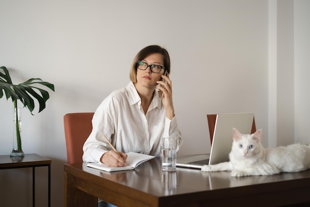 Serious middleaged business woman wearing eyeglasses white linen shirt with long straight hair worki