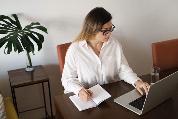 Serious middleaged business woman wearing eyeglasses white linen shirt with long straight hair worki