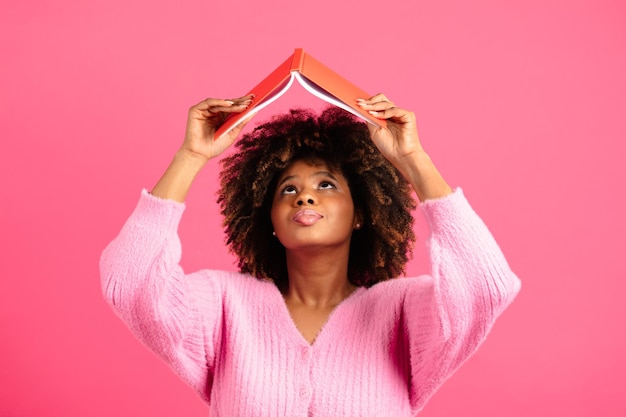 Serious millennial african american curly female student in casual lifts book up reads diary look up