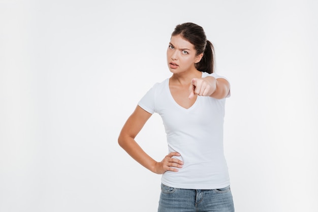 Serious model in t-shirt showing at front isolated white wall