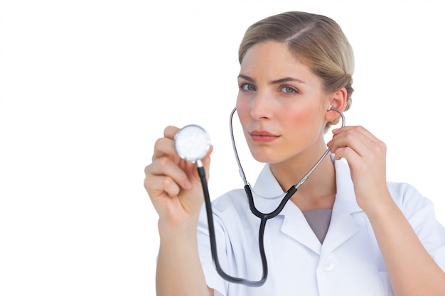 Serious nurse listening with stethoscope