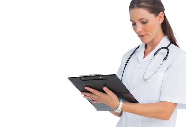 Serious nurse writing on clipboard on white background