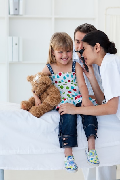 Serious patient examing littl girl's ears