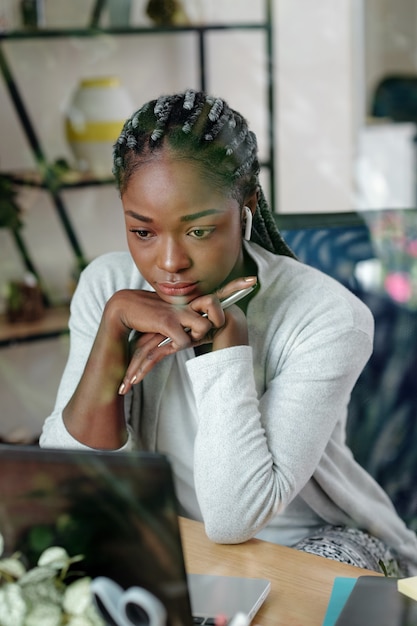 Serious pensive businesswoman reading on laptop screen when working on laptop at home