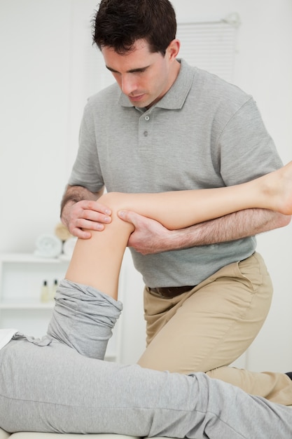 Serious physiotherapist looking at the knee of a patient