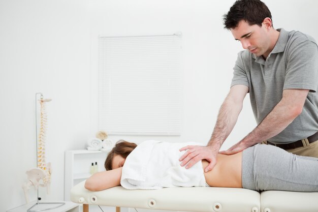 Serious practitioner massaging the lower back of a woman