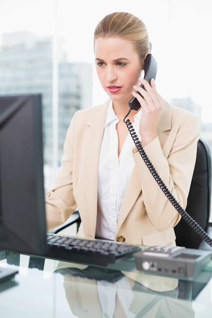 Serious pretty businesswoman answering the phone