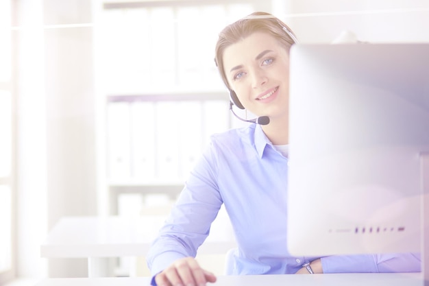 Serious pretty young woman working as support phone operator with headset in office