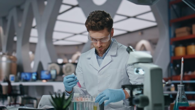 Serious researcher examining liquid in test tubes working laboratory close up