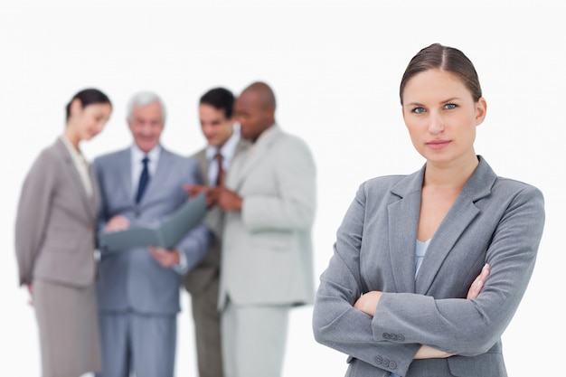 Serious saleswoman with folded arms and team behind her