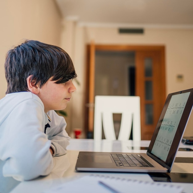 Serious school boy concentrated while studying maths at home Home school and distance education concept