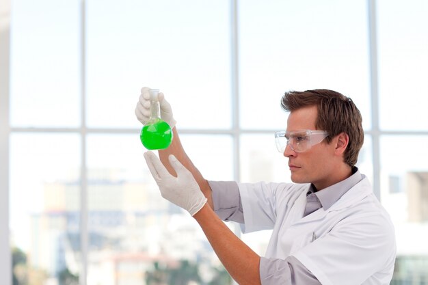 Serious scientist examining a chemical test-tube with copy-space