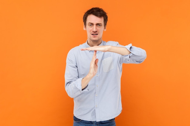 Serious self confident man making timeout gesture demonstrating limit asking to stop