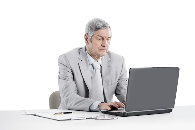 Serious senior businessman working on laptop while sitting at his Desk