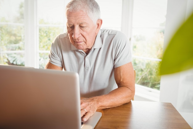 Serious senior man using his laptop at home