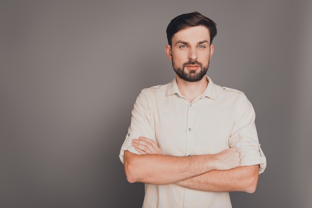 Serious strict businessman with crossed hands on gray