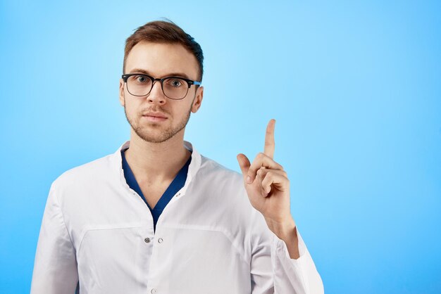https://img.freepik.com/premium-photo/serious-strict-doctor-glasses-white-coat-raised-his-finger-up-makes-remark-isolated-blue-background_154092-14615.jpg
