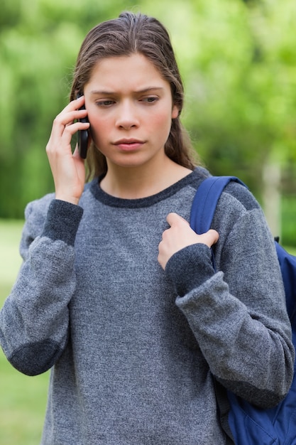 Serious student looking down while talking on the phone