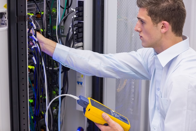 Photo serious technician using digital cable analyzer on server