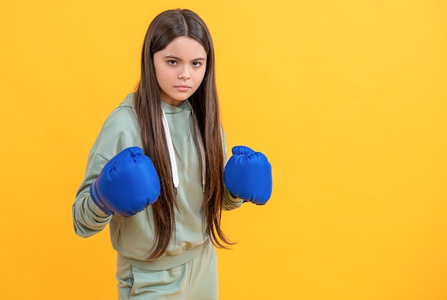 Serious teen boxing girl on background photo of teen boxing girl wearing gloves