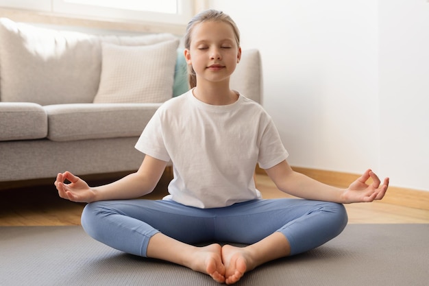 Foto l'adolescente caucasico teenager serio in abbigliamento sportivo con la meditazione degli occhi chiusi pratica lo yoga gode