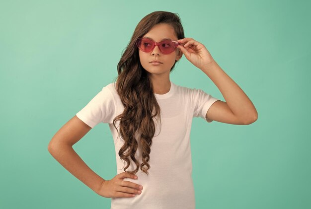 Serious teen girl long curly hair in sunglasses casual style on blue background summer style