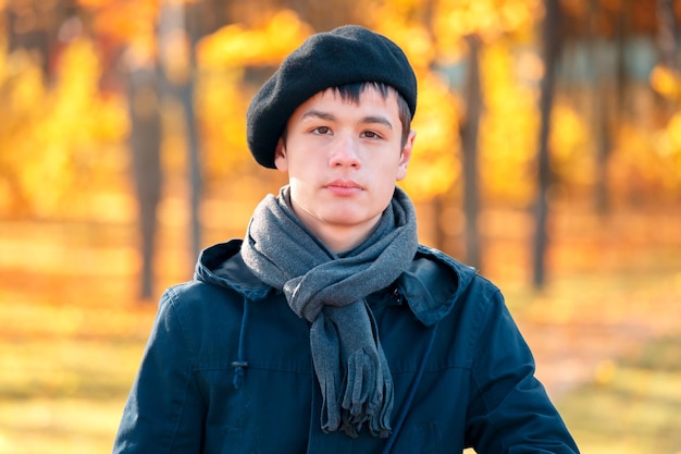 Serious teenage boy in the autumn sunny park