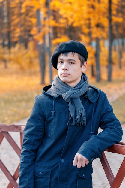Photo serious teenage boy in the autumn sunny park