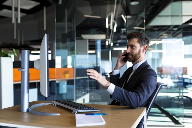 Serious and thoughtful male entrepreneur working in the office at the computer in a business suit