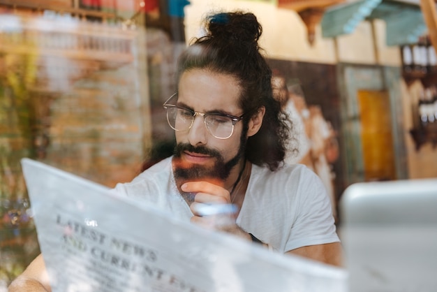 Photo serious thoughtful man reading an article while being in the cafe