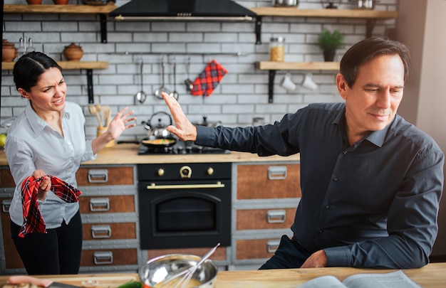 Serious and upset man sit at table in kitchen.