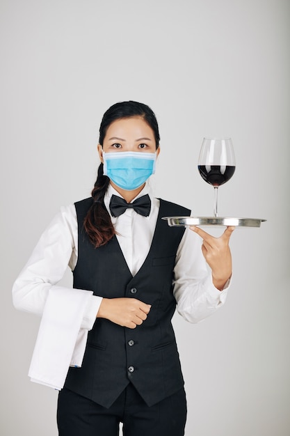 Serious waitress carrying wine