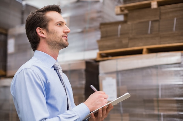 Serious warehouse manager checking inventory