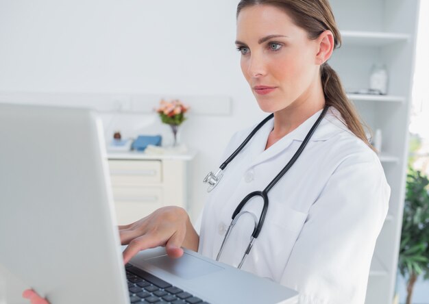 Serious woman doctor using a laptop