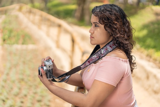 Serious woman holding a camera in a park