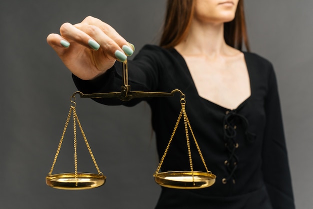Serious woman holding the justice scale on dark background
