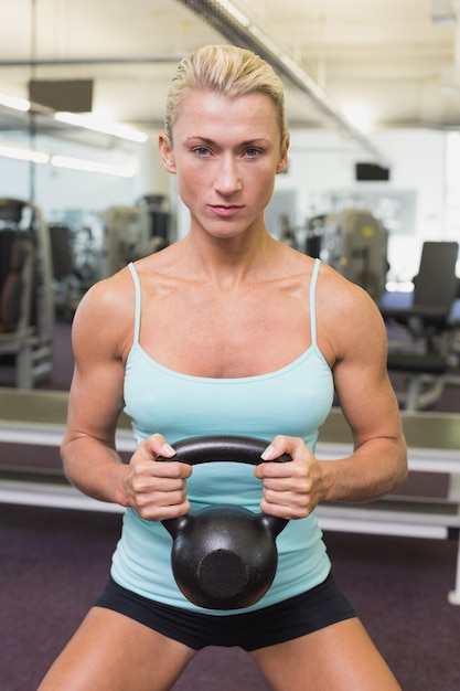 Campana di sollevamento del bollitore della donna seria in palestra