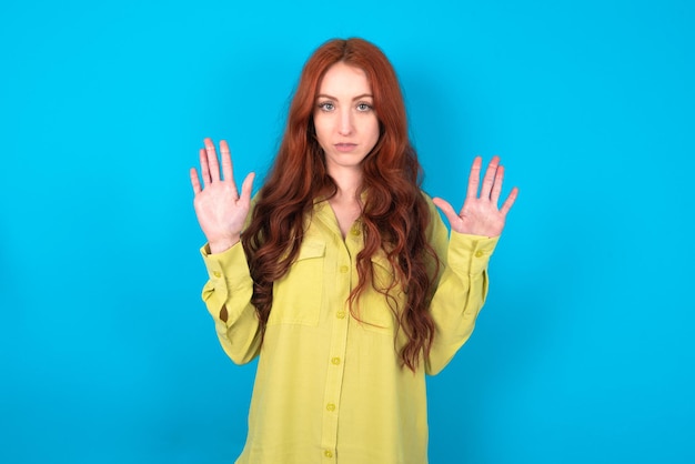 Serious woman pulls palms towards camera makes stop gesture asks to control your emotions