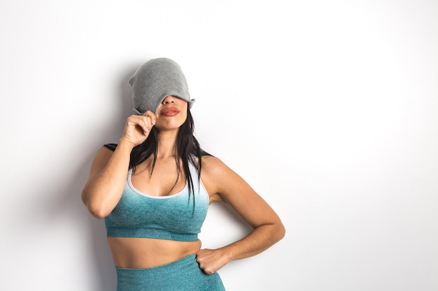 Serious woman in sportswear covering face with hat