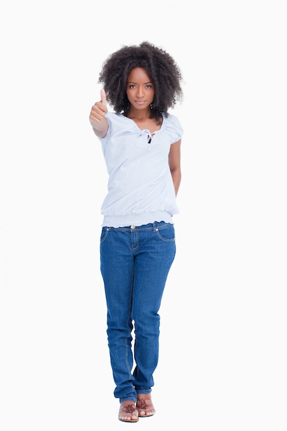 Serious woman standing upright with her thumbs up and a hand on her back