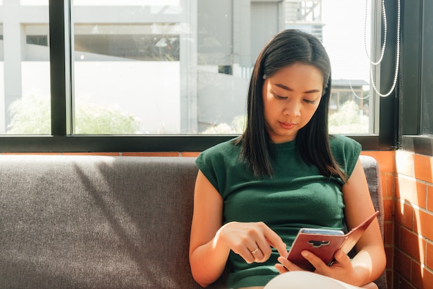 深刻な女性は、カフェの隅にあるソファーで自分のスマートフォンを使います。